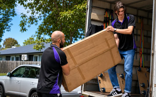 Two SwiftMove movers loading a timber cabinet into their truck
